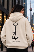 The Key — Al-Awda cream hoodie with antique key and Still Ours back print