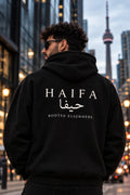 The Statement — Hawiya black hoodie with HAIFA and Rooted Elsewhere back print